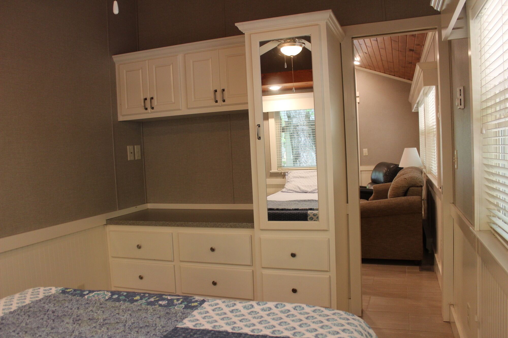 A compact bedroom with a bed, a built-in wardrobe, and a small seating area.