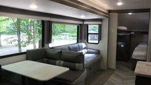 A compact RV interior with a dining area, seating, and a kitchenette. - RV Rental #13 Sleeps 6 people (Empire)