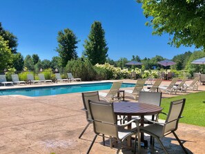 Relax by the pool surrounded by lush greenery and comfortable seating options.