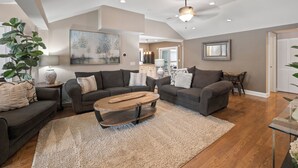 A spacious living room with a large sectional sofa, a coffee table, and a dining area.