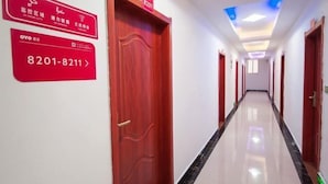 Un couloir d’hôtel avec des portes rouges, un plafond doté d’un éclairage encastré et un panneau indiquant les numéros de chambre 8201 à 8211.