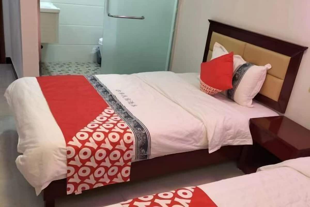 Ein Hotelzimmer mit einem Bett, einem Nachttisch und einem im Hintergrund sichtbaren Badezimmer.