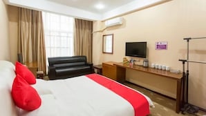 Une chambre d’hôtel avec un lit, un bureau, une télévision et une fenêtre avec des rideaux.