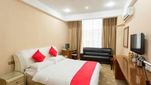 Une chambre d’hôtel avec un lit, un bureau, une télévision et une fenêtre avec des rideaux.