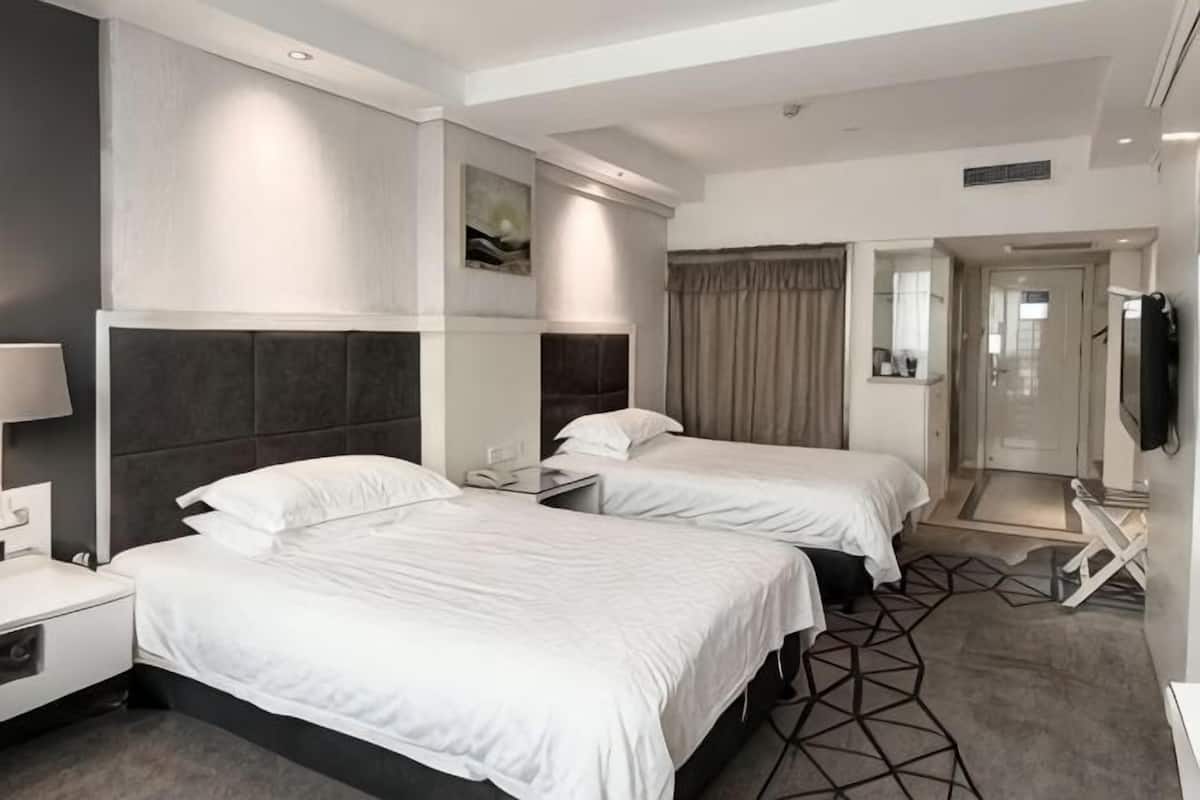 Une chambre d’hôtel avec deux lits, une télévision, un bureau et un miroir.