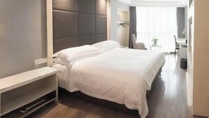 Une chambre d’hôtel moderne, dotée d’un grand lit, d’une table de chevet, d’un petit bureau et d’une chaise.