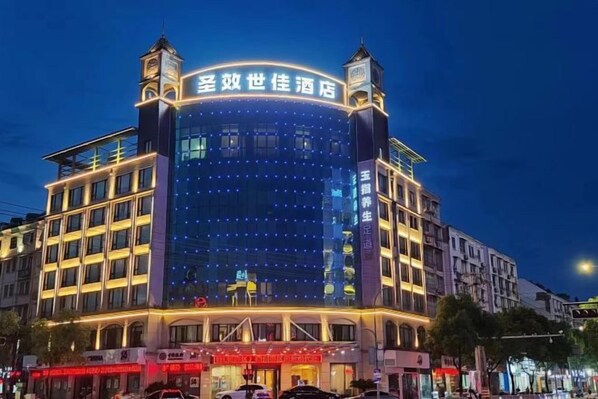 A multi-story hotel with a prominent sign at the top, multiple balconies, and a well-lit facade.