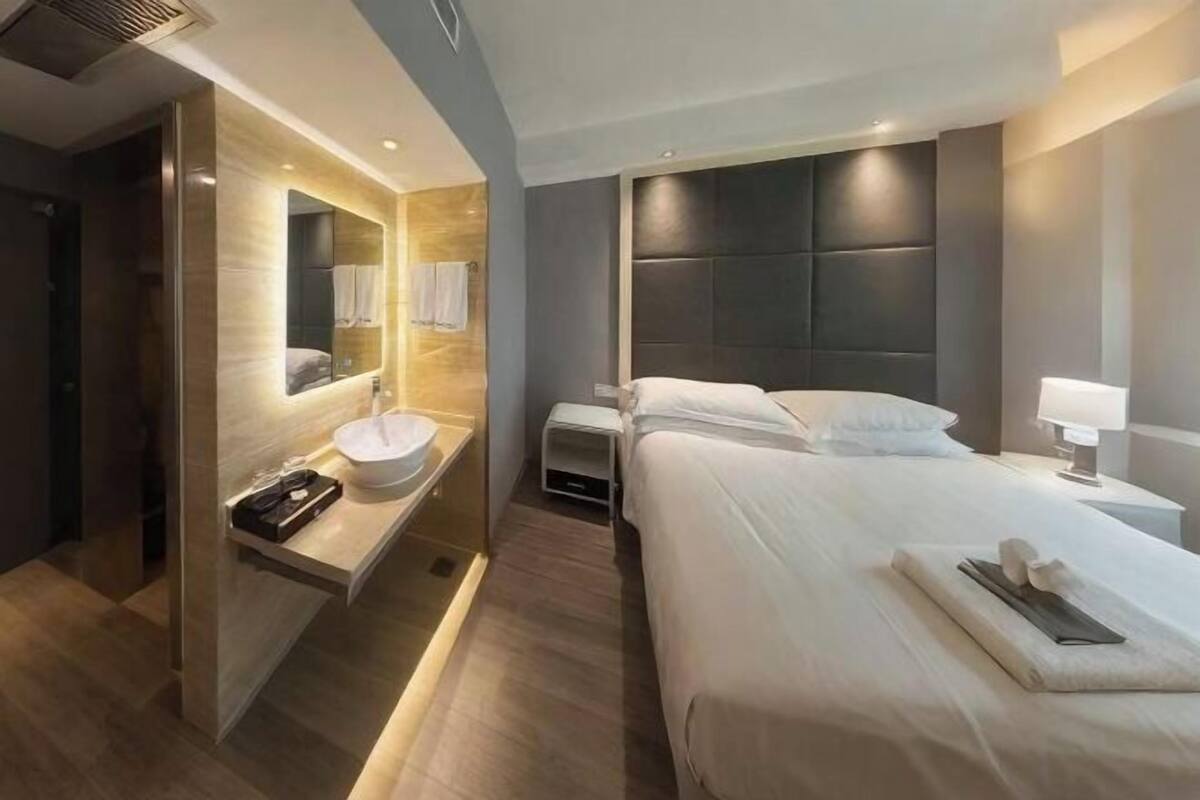 Une chambre d’hôtel moderne avec un grand lit, une table de chevet et un lavabo intégré.