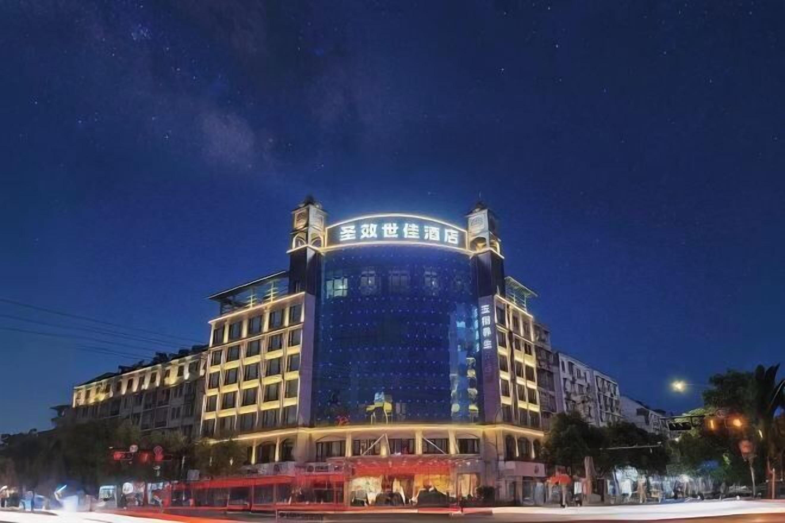 A hotel with a prominent curved facade and illuminated signage.