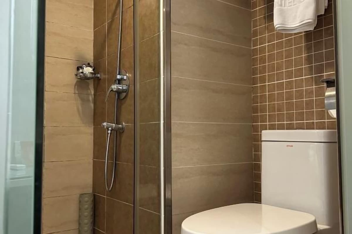 A bathroom with a glass-enclosed shower, a white toilet, and a tiled wall.