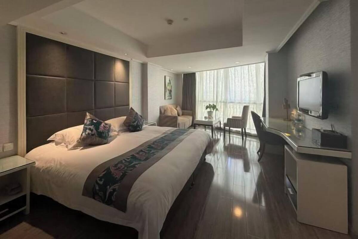Une chambre d’hôtel moderne équipée d’un grand lit, d’un bureau, d’une chaise et d’un téléviseur.