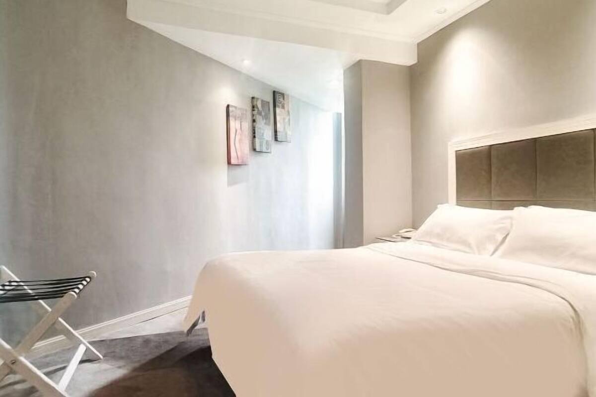 Une chambre à coucher avec un lit, une chaise et des œuvres d’art accrochées au mur.