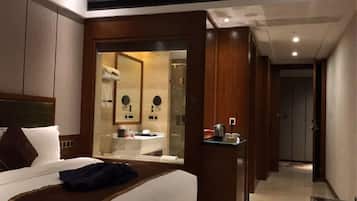 A hotel room with a bed, a bedside table, a mirror, and a view into the bathroom.