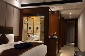 A hotel room with a bed, a bedside table, a mirror, and a view into the bathroom. - Wisconsin Spa Hotel (Tianjin)