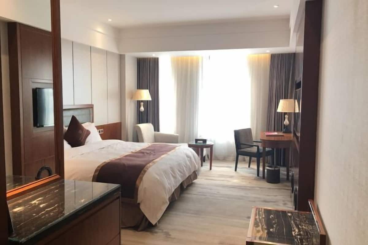 Hotellihuone, jossa on sänky, työpöytä, tuoli, televisio ja kylpyhuone.