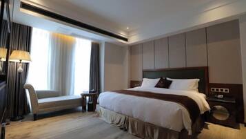 A hotel room with a large bed, a bedside table, a chair, and a window with curtains.