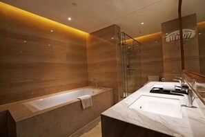 Een moderne badkamer met een badkuip, een douchecabine van glas en een marmeren wastafel.