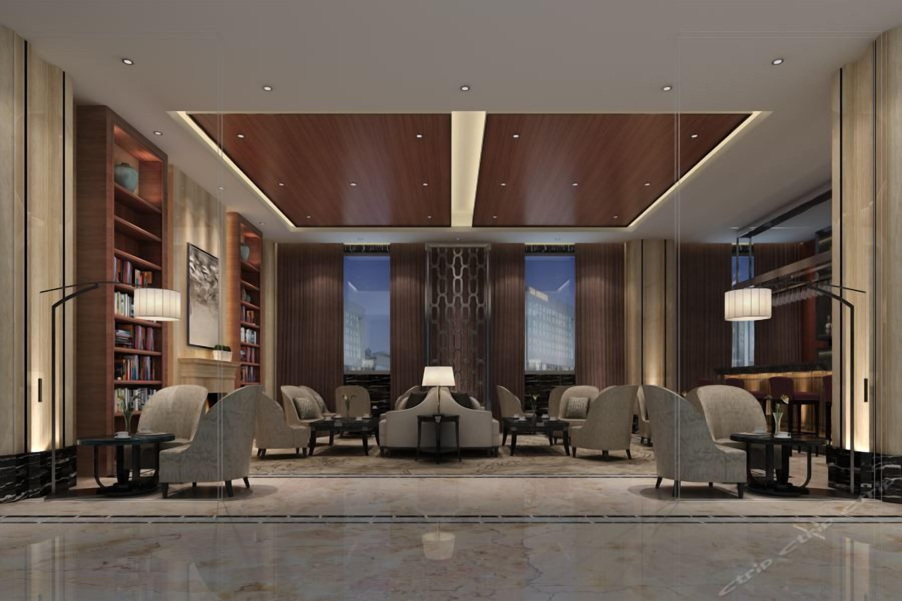 A modern lobby with a central seating area, bookshelves, and a large window.
