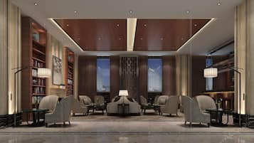 A modern lobby with a central seating area, bookshelves, and a large window.