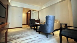 A hotel room with a wooden floor, a dining table with chairs, a sofa, and a TV on the left side. - Wisconsin Spa Hotel (Tianjin)