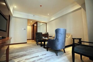 A hotel room with a wooden floor, a dining table with chairs, a sofa, and a TV on the left side. - Wisconsin Spa Hotel (Tianjin)