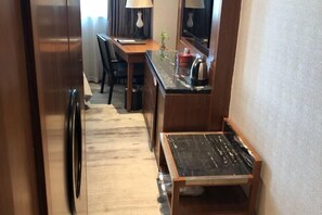 A compact hotel room with a wooden desk, a small table, a mirror, and a kitchenette area. - Wisconsin Spa Hotel (Tianjin)