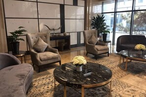 A lobby with two armchairs, a sofa, a coffee table with flowers, and a fireplace. - Wisconsin Spa Hotel (Tianjin)