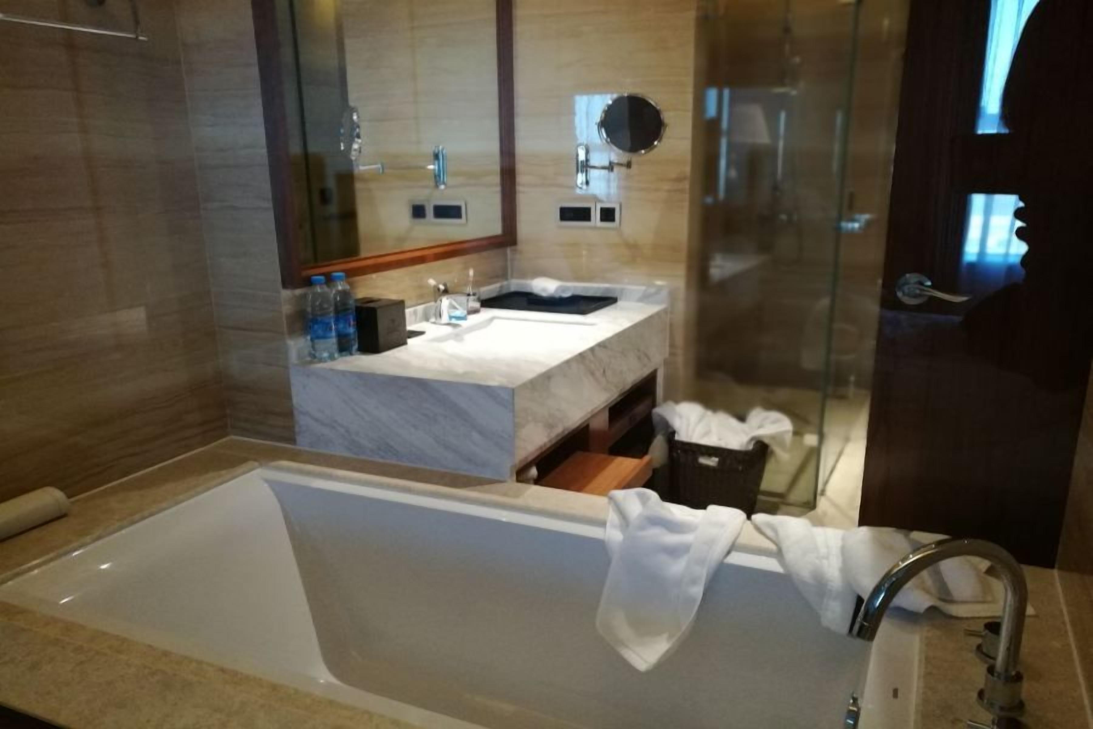 A modern bathroom with a large bathtub, a vanity with a mirror, and a shower area.
