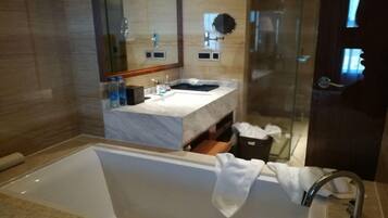 A modern bathroom with a large bathtub, a vanity with a mirror, and a shower area.