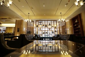 A lobby with a reception desk, seating area, and decorative shelves with vases. - Wisconsin Spa Hotel (Tianjin)