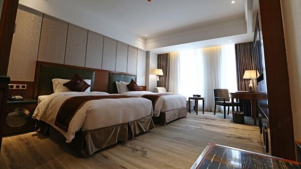 Een hotelkamer met twee bedden, een bureau en een stoel.