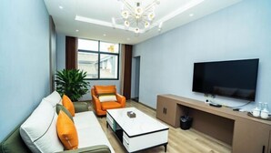 Uma sala de estar moderna com um sofá, poltrona, mesa de centro, televisão e uma planta.