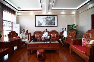 A room with a wooden coffee table, chairs, a television, and a framed picture on the wall.