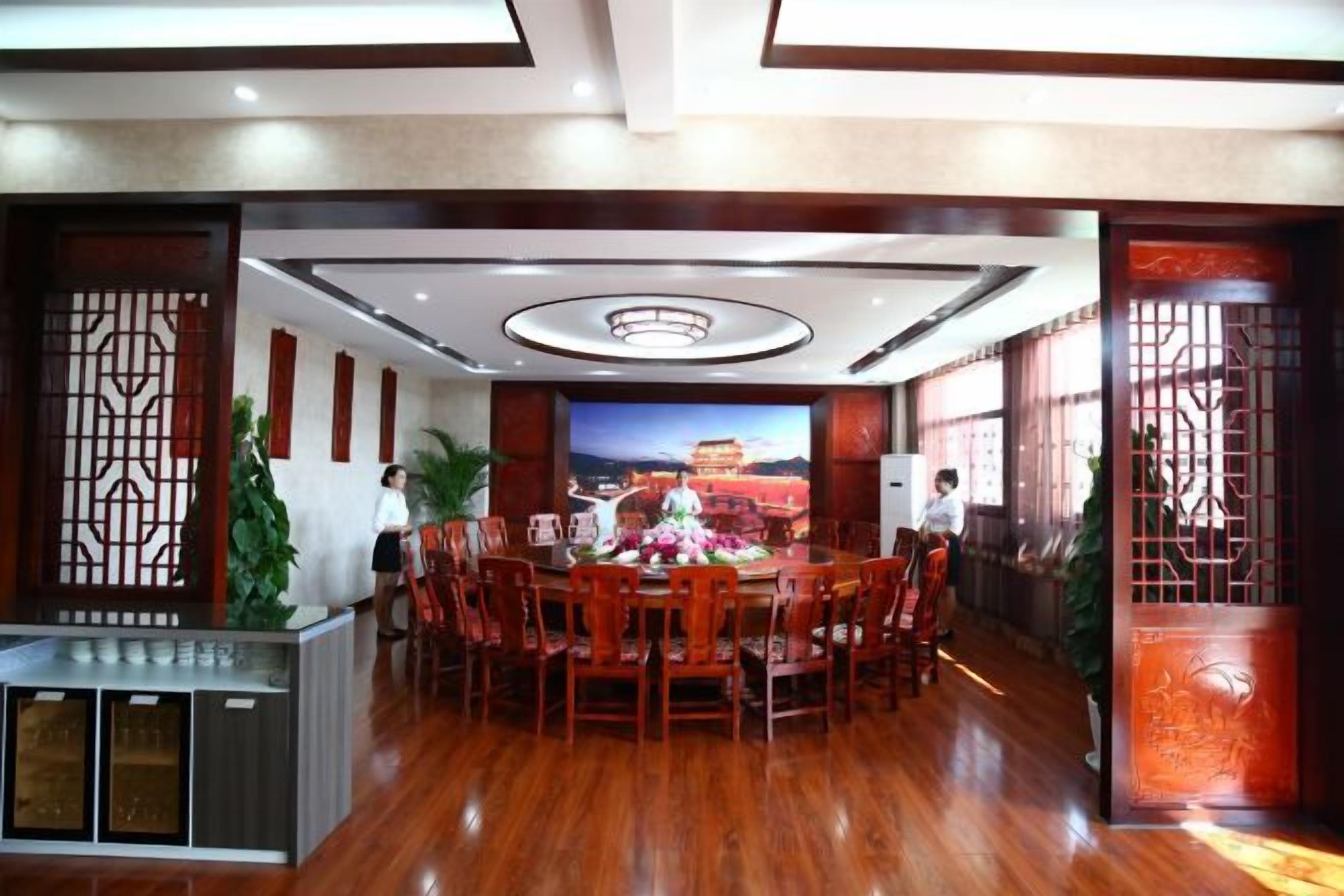 A conference room with a round table, chairs, a TV screen, and decorative screens.