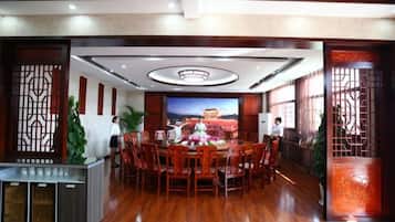 A conference room with a round table, chairs, a TV screen, and decorative screens.