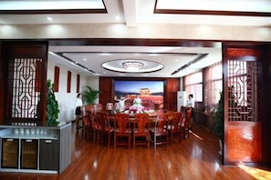 A conference room with a round table, chairs, a TV screen, and decorative screens. - Taowowo Holiday Hotel (Jianshui)