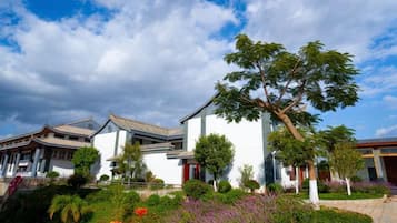 A traditional building with a large tree in front, surrounded by well-maintained gardens.