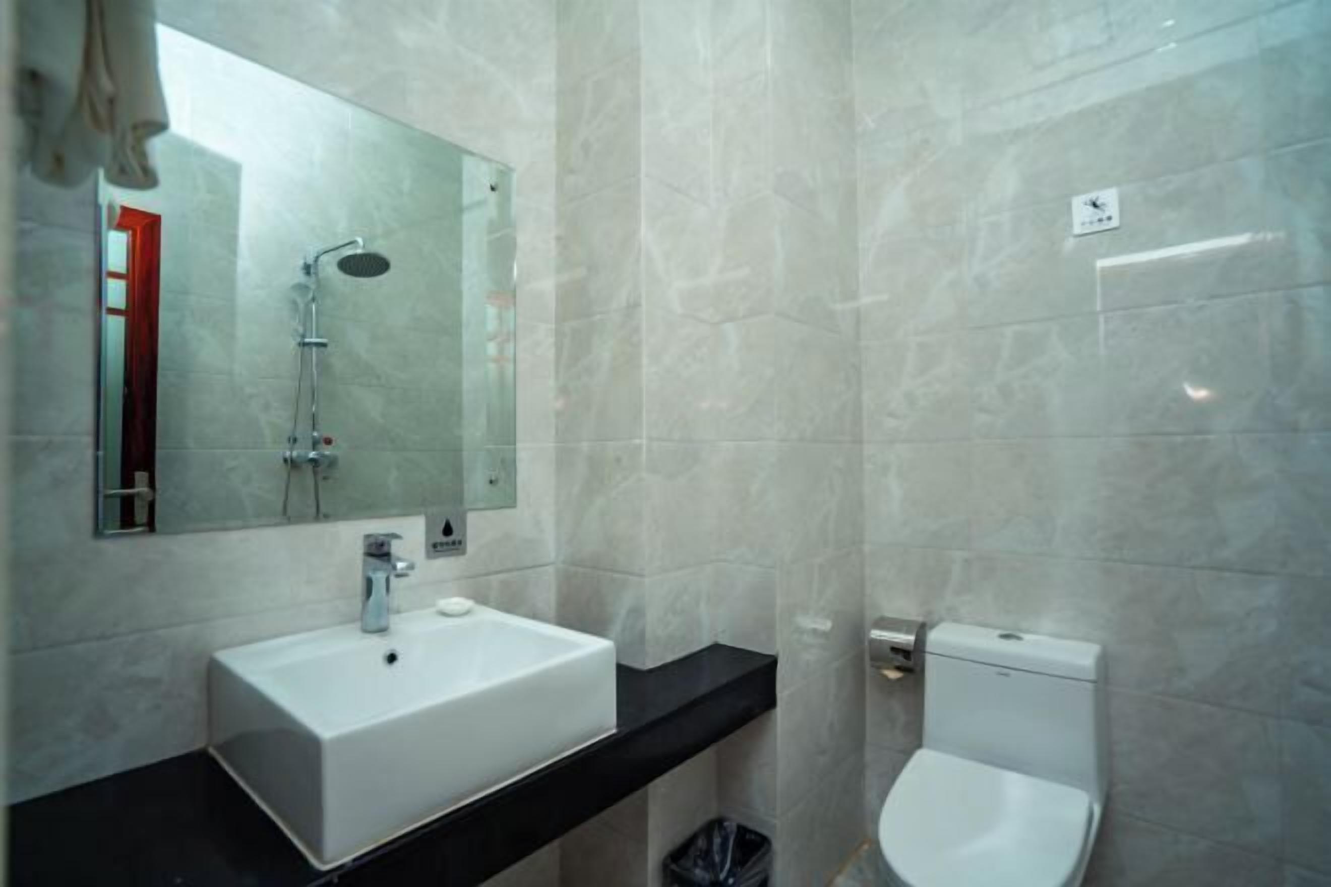 A bathroom with a white sink, a mirror, a shower, and a toilet.