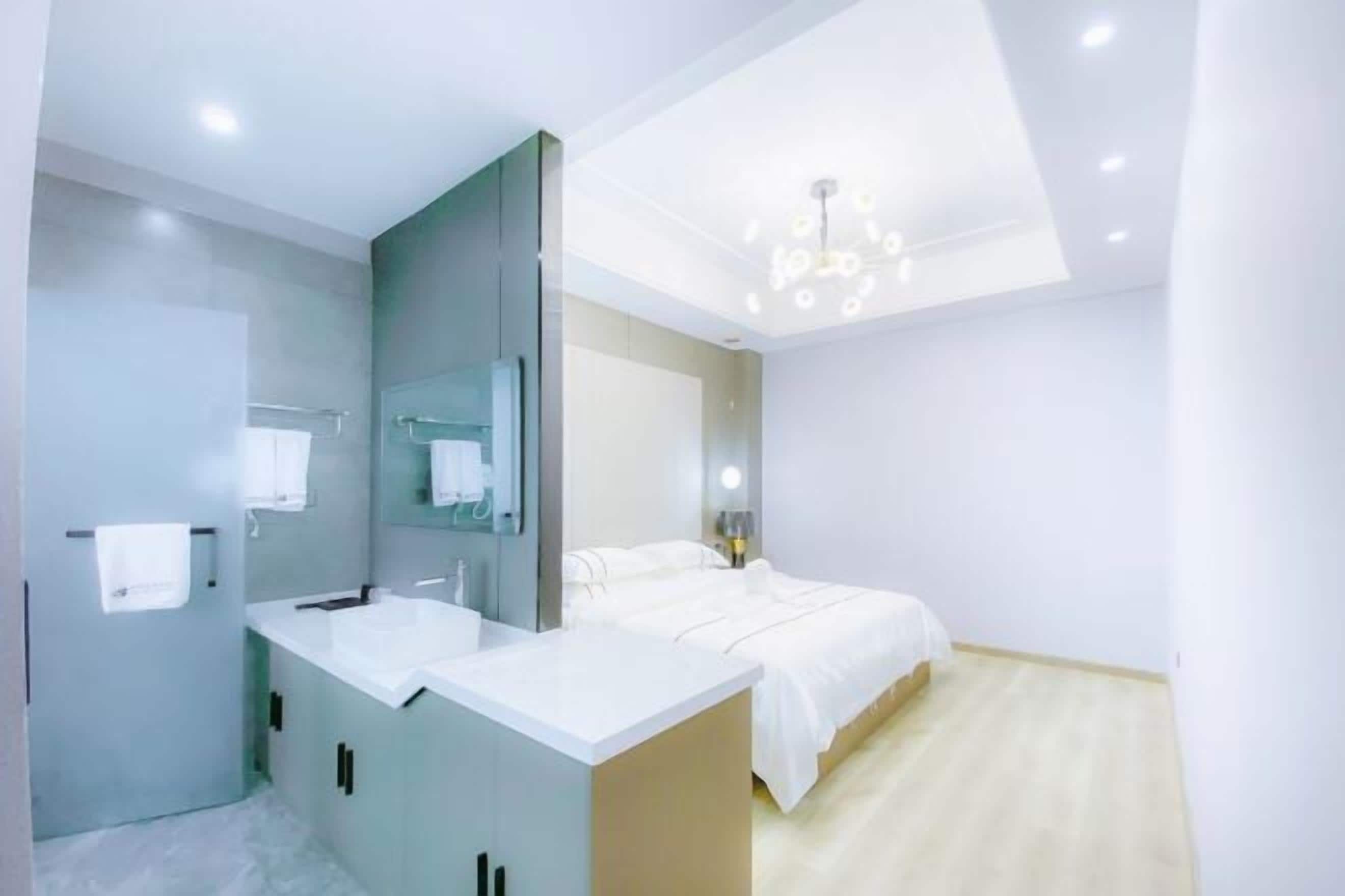A modern bedroom with a bed, a vanity with a mirror, and a ceiling light fixture.