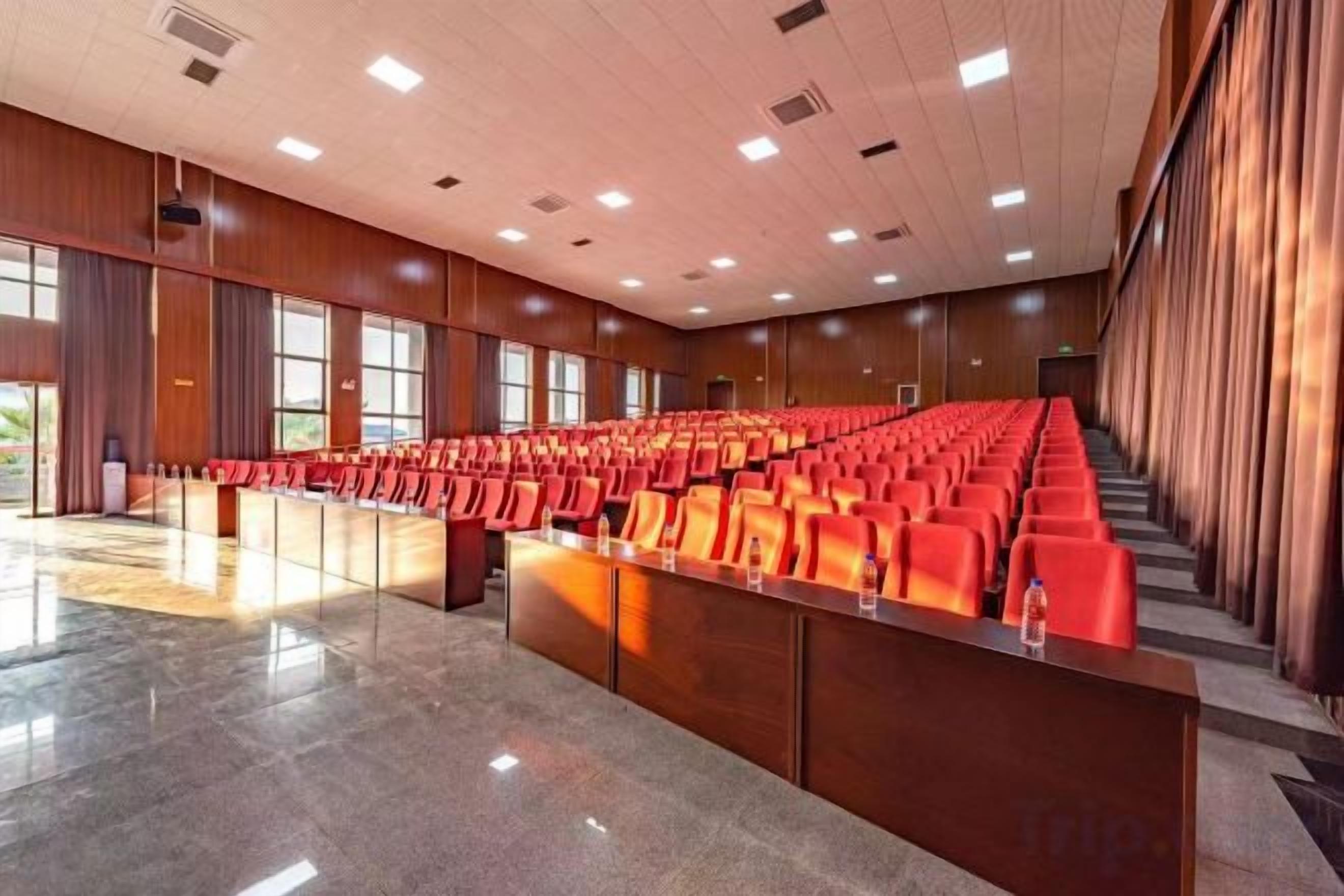 A conference room with rows of chairs, a podium, and a large window.