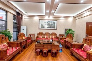 A traditional meeting room with wooden furniture, a central table, and a framed picture on the wall. - Taowowo Holiday Hotel (Jianshui)
