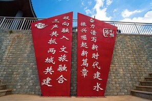 Two red banners with white Chinese characters against a brick wall. - Taowowo Holiday Hotel (Jianshui)