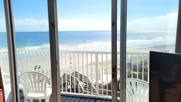 Ein Balkon mit Blick auf Strand und Meer.