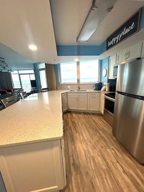A modern kitchen with a large island, stainless steel appliances, and a view of the ocean. - Oceanfront with 2 Balconies |Seawatch NT 311 (Myrtle Beach)