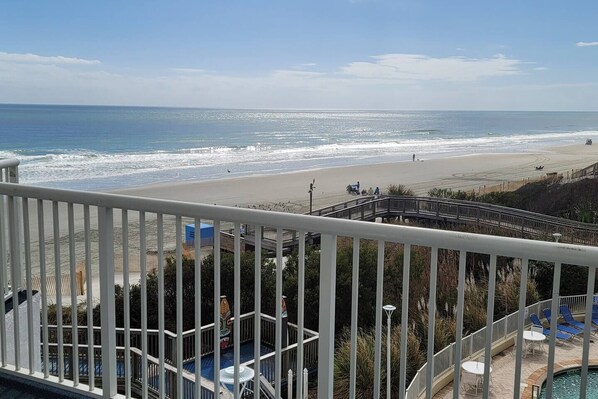 A beach view from a balcony with a pool and lounge chairs. - Oceanfront with 2 Balconies |Seawatch NT 311 (Myrtle Beach)