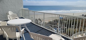 A balcony with a white table and chairs, overlooking a beach and ocean. - Oceanfront with 2 Balconies |Seawatch NT 311 (Myrtle Beach)