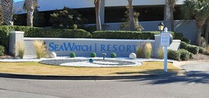 A sign for SeaWatch Resort with a landscaped area featuring a circular garden with rocks and small trees. - Oceanfront with 2 Balconies |Seawatch NT 311 (Myrtle Beach)