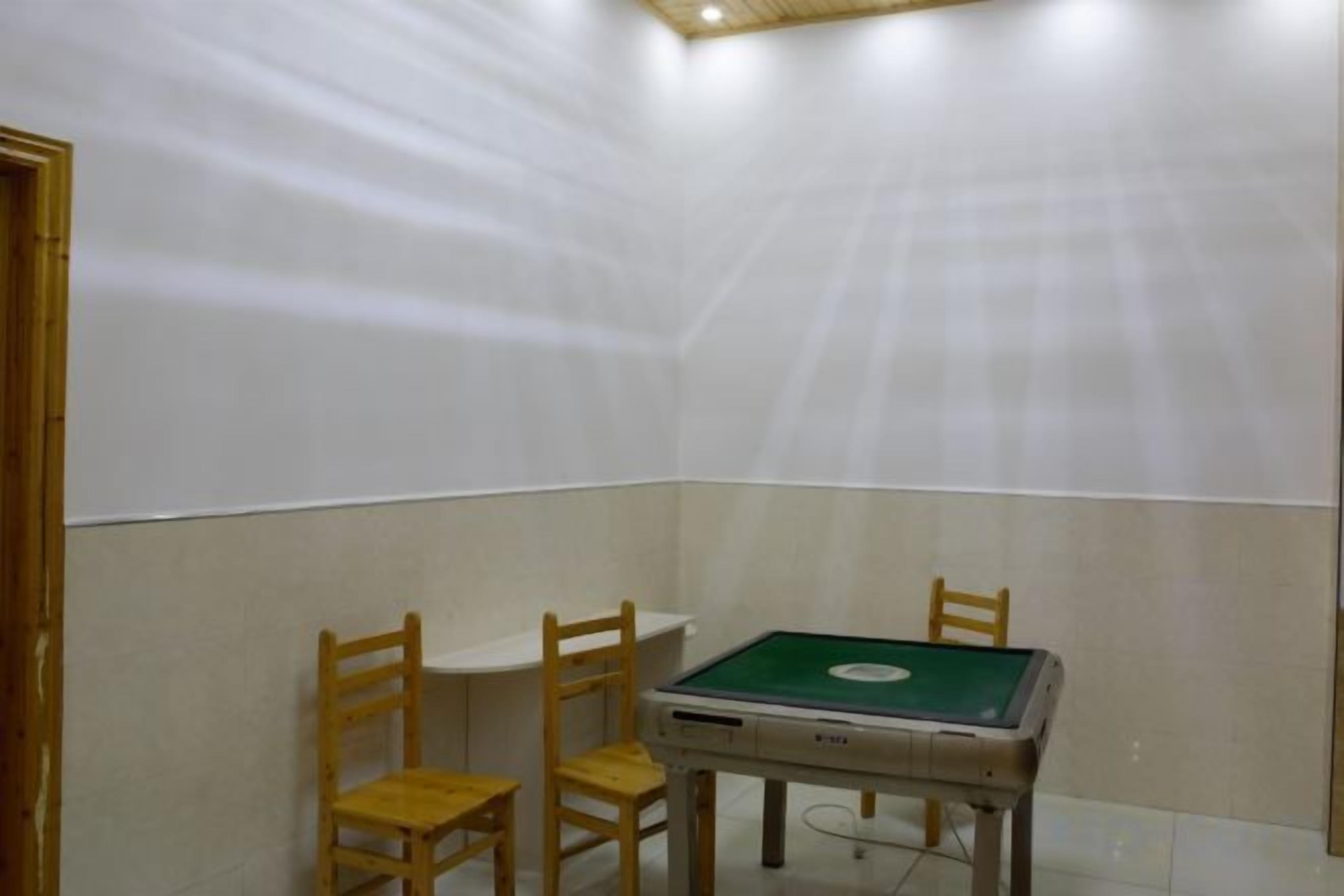 A room with a pool table, two wooden chairs, and a ceiling light fixture.