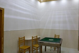 A room with a pool table, two wooden chairs, and a ceiling light fixture.
