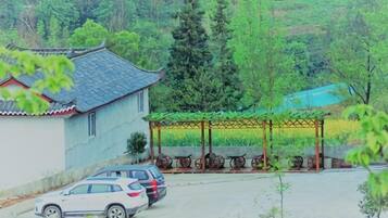 A traditional building with a tiled roof, a covered outdoor seating area with tables and chairs, and a parking lot with cars.